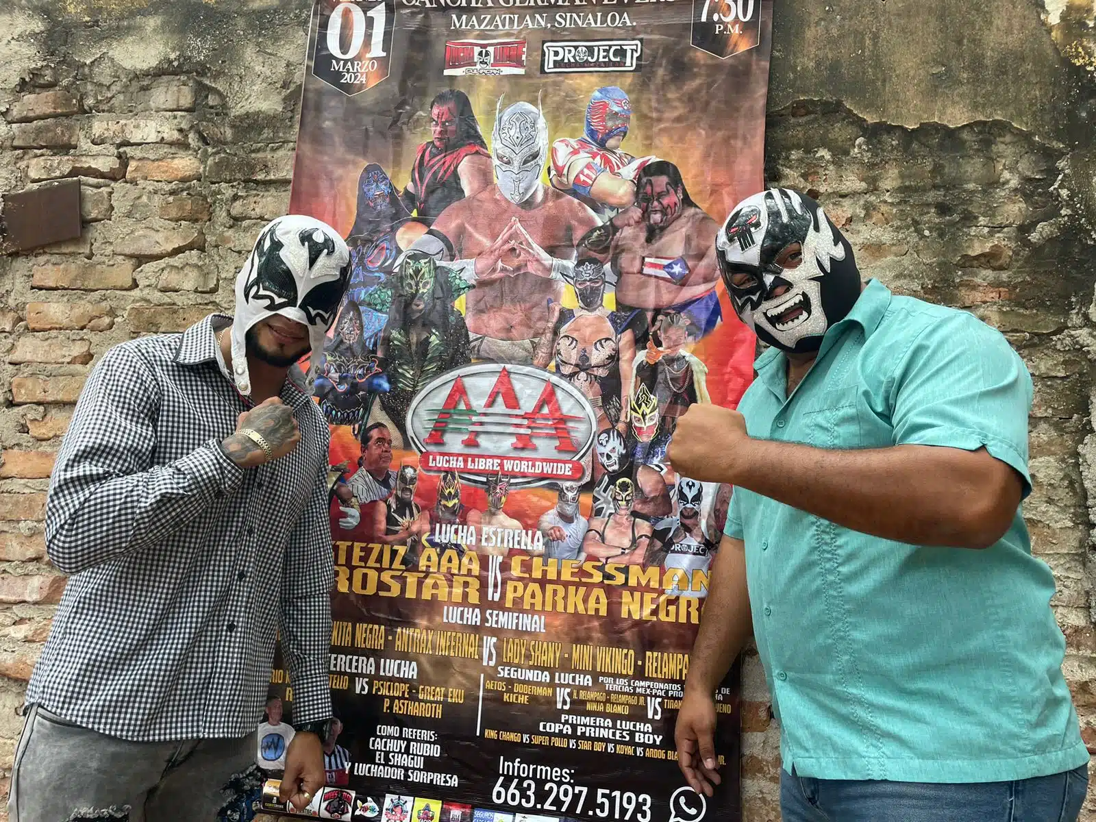 Mercury y Antraz Infernal junto cartelón que da promoción a su pelea de lucha libre en Mazatlán