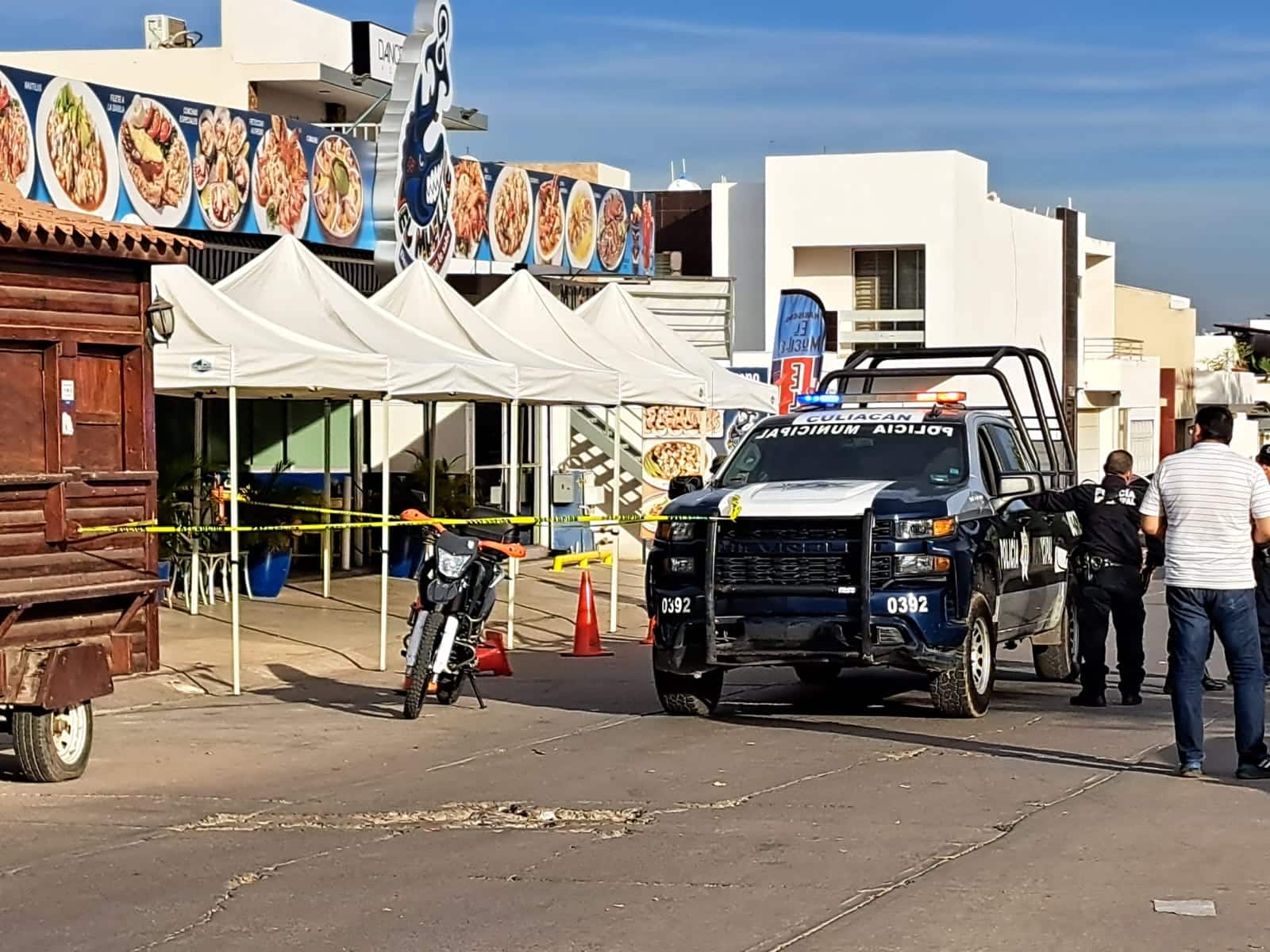 Patrulla de la Policía Municipal de Culiacán, una motocicleta y cinta amarilla delimitando el área del restaurante donde murió Abel