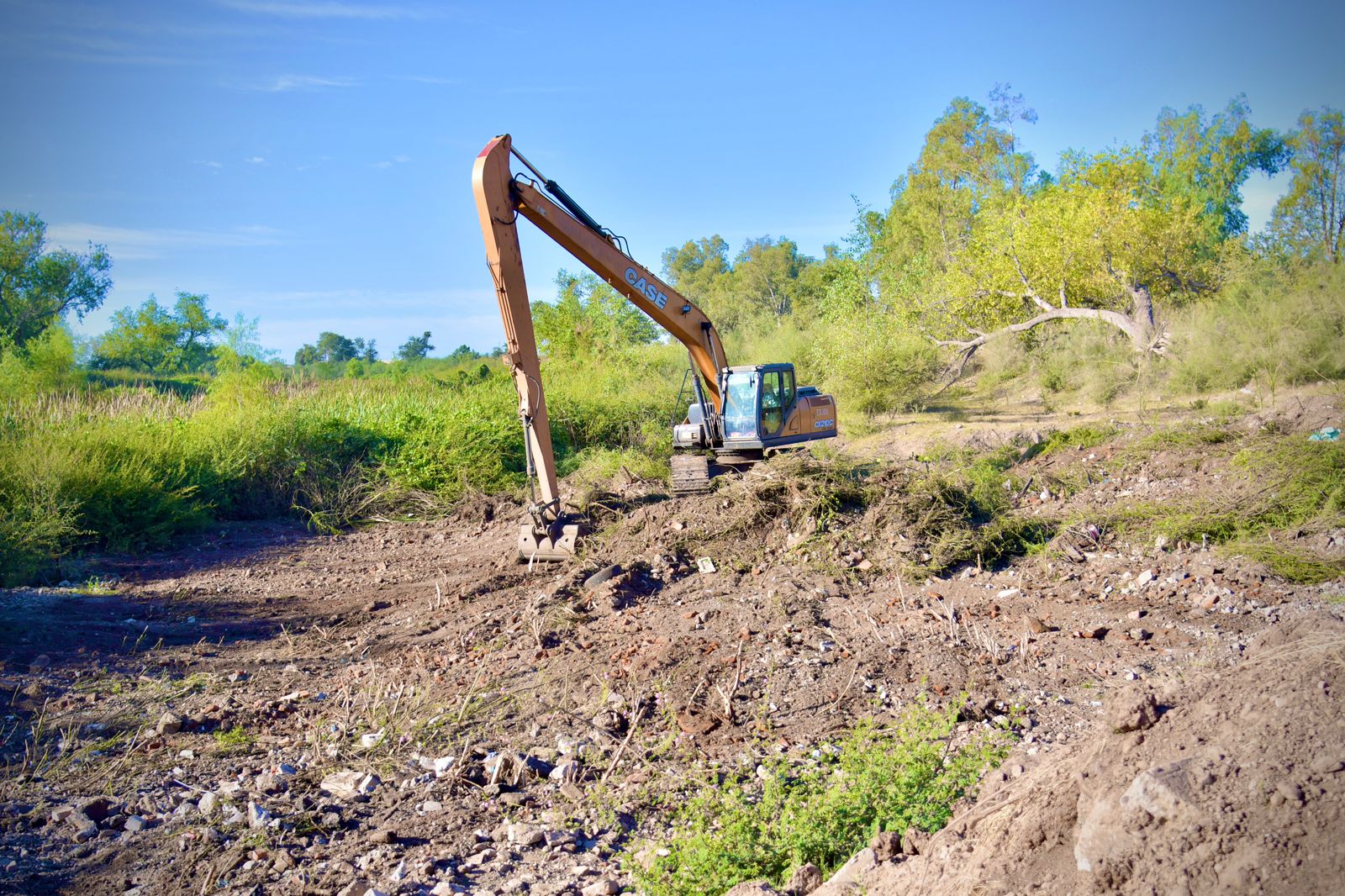 Maquina retroexcavadora haciendo limpieza en el río Évora en Guamíuchil
