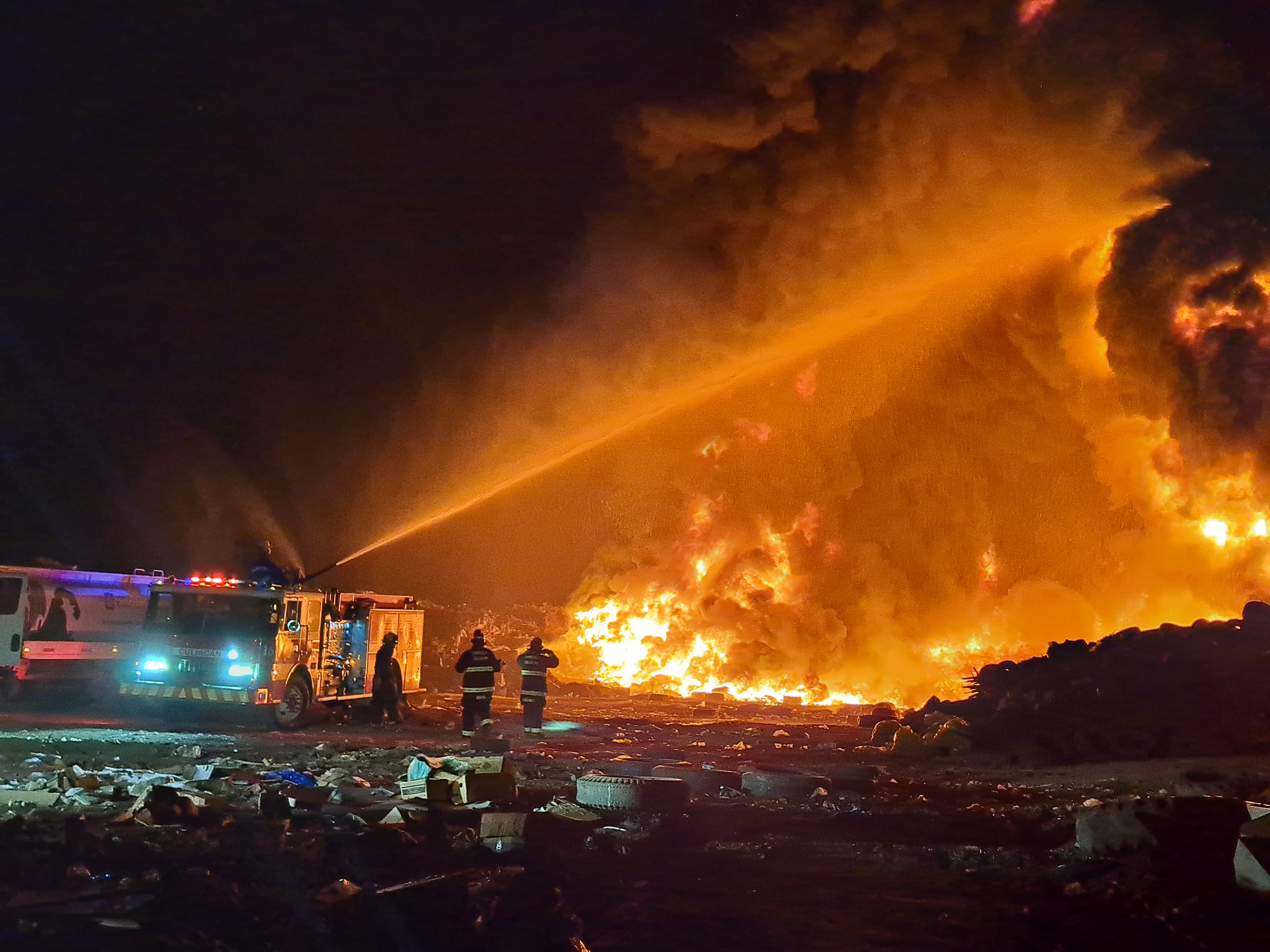 Toma abierta a la máquina de Bomberos mientras rocía agua a la columna de humo y fuego durante incendio del basurón municipal de Culiacán