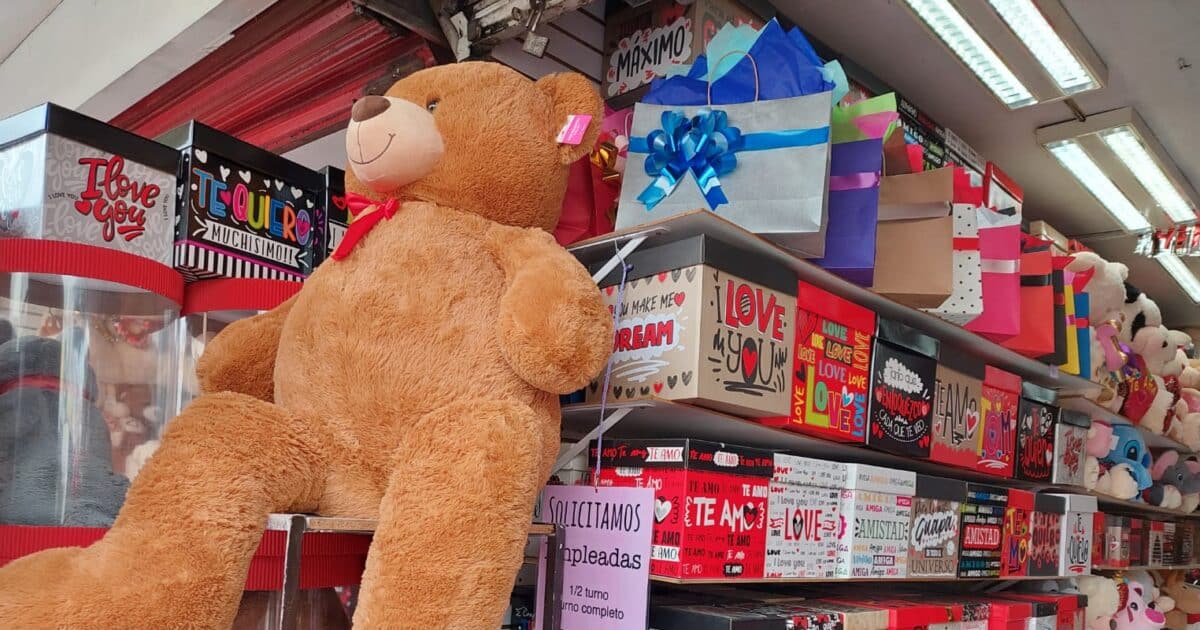 Oso de peluche sobre una mesa con cajas de regalo atrás y por delante