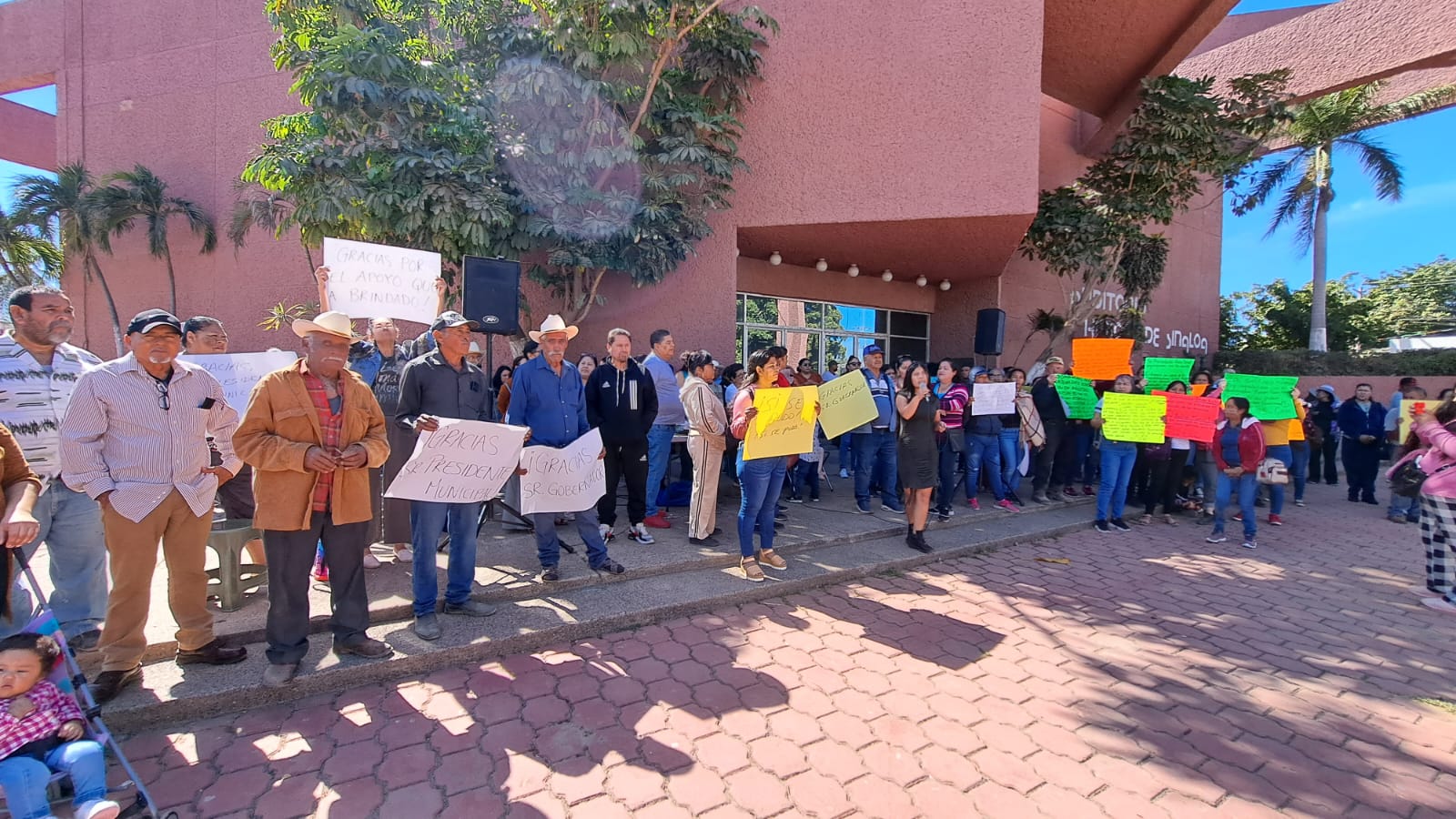 Integrantes de la Coordinadora Estatal para la Defensa del Derecho Humano a la Vivienda y Reservas Territoriales afuera de las instalaciones del Palacio Municipal en Guasave con pancartas de agradecimiento