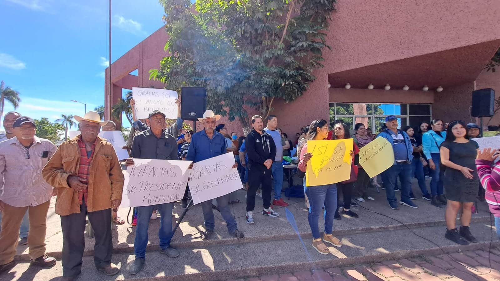 Integrantes de la Coordinadora Estatal para la Defensa del Derecho Humano a la Vivienda y Reservas Territoriales afuera de las instalaciones del Palacio Municipal en Guasave con pancartas de agradecimiento