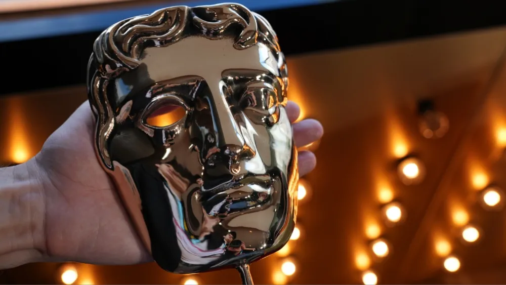 Una sostiene la mascarilla dorada de los premios BAFTA