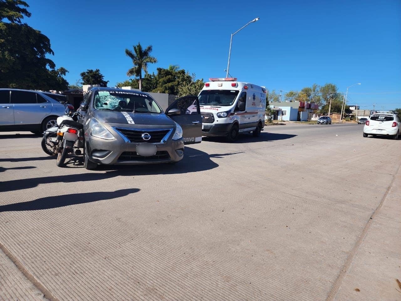Taxi impactado contra una motocicleta. Hay una ambulancia de Summa al fondo