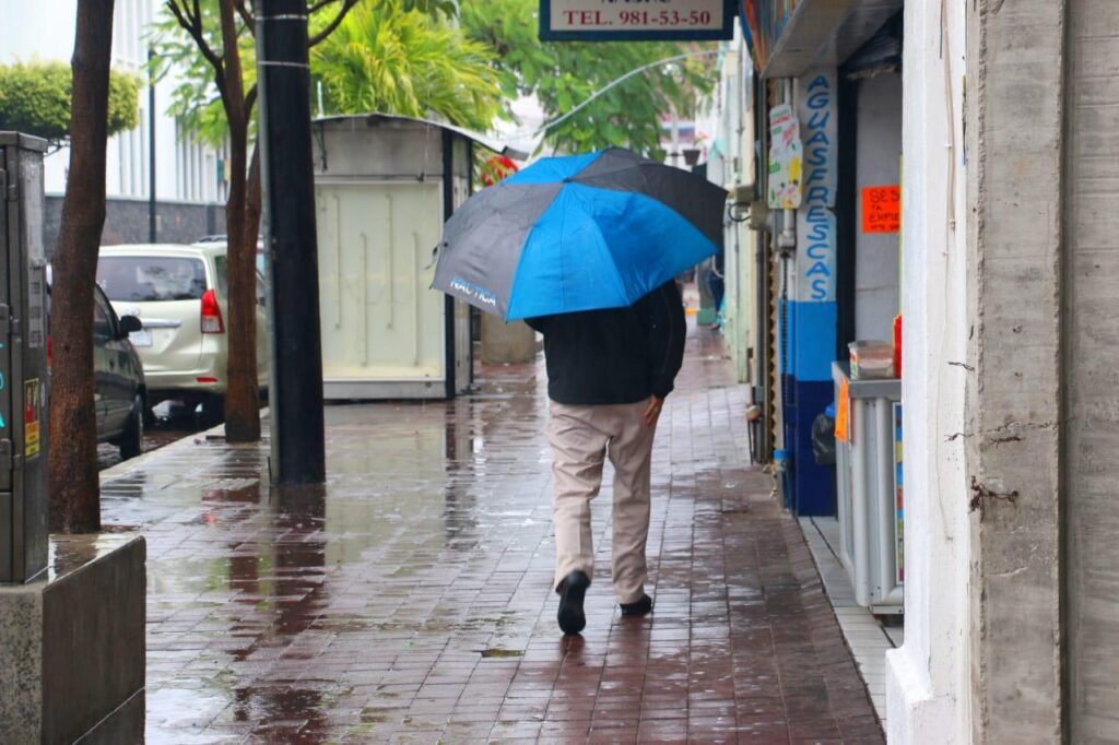 Persona utilizando paraguas color azul por lluvias