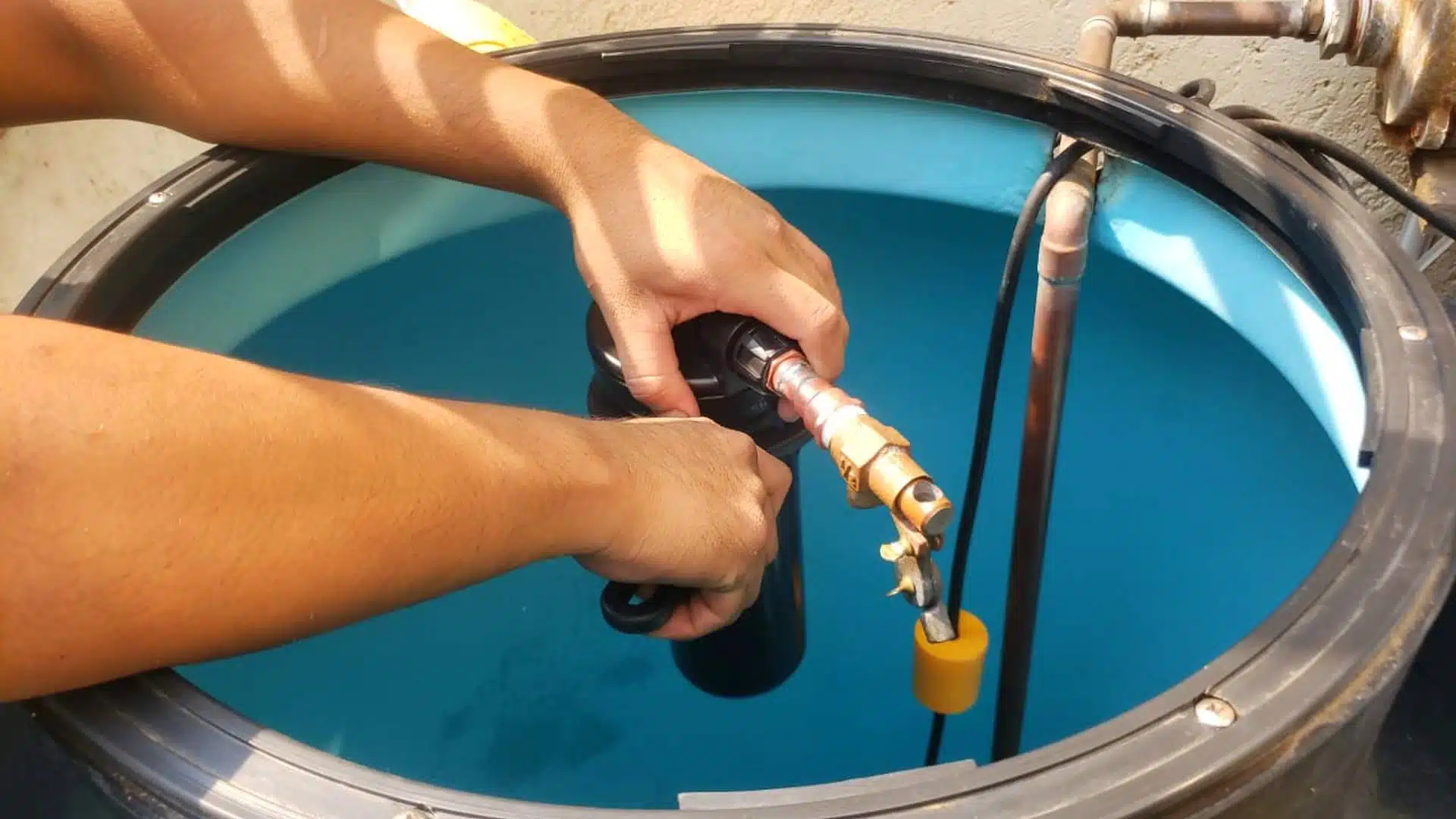 Una persona instalando un filtro en la entrada de agua en un tinaco