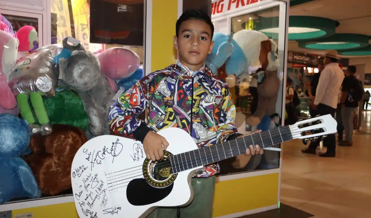 El pequeño Sergio mostrando su guitarra firmada por los artistas que estuvieron presentes en la Plaza Acaya