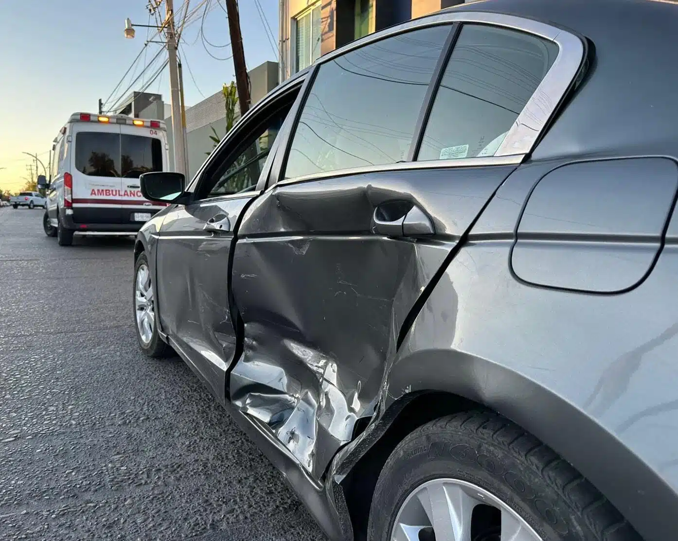 Vehículo color gris con un golpe en el costado izquierdo