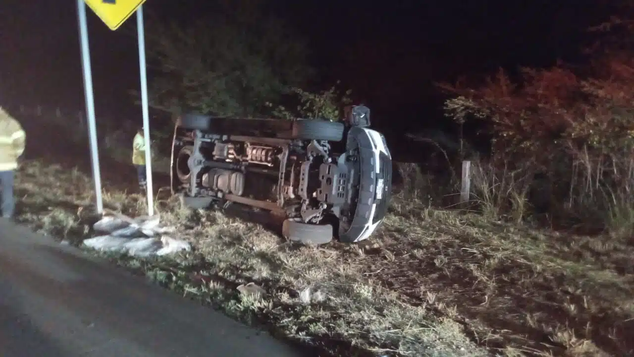 Camioneta de modelo reciente volcada sobre su costado a un lado de la carretera