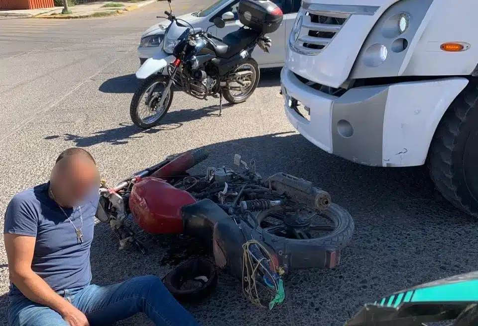 Ángel Guadalupe junto a su motocicleta en el pavimento tras ser atropellado por un camión en Guasave
