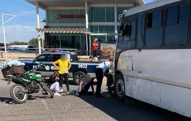 Personas mirando a Ángel Guadalupe junto a su motocicleta en el pavimento tras ser atropellado por un camión en Guasave