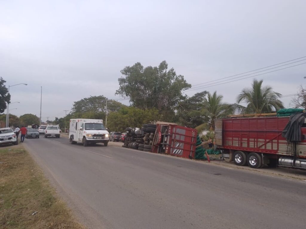 Carros pasando por el lugar donde un tráiler tipo torton cargado de chiles terminó volcado sobre el lado del copiloto en Villa Unión