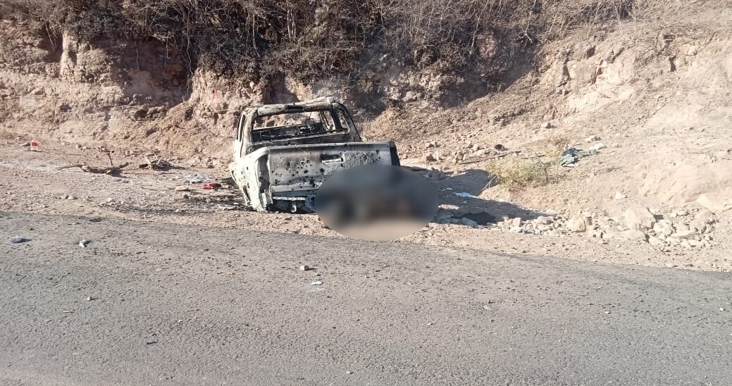 Camioneta quemada a orilla de una carretera y un cuerpo sin vida pegada a la parte trasera de la unidad