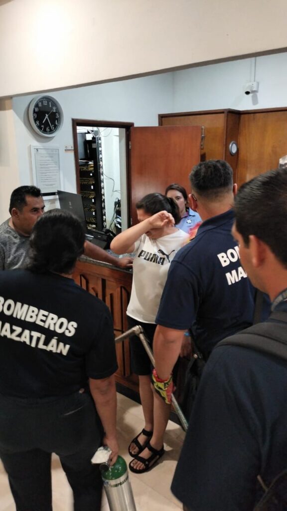 Elementos de Bomberos y una persona llorando en el lugar donde fue rescatada en el elevador de un hotel en Mazatlán