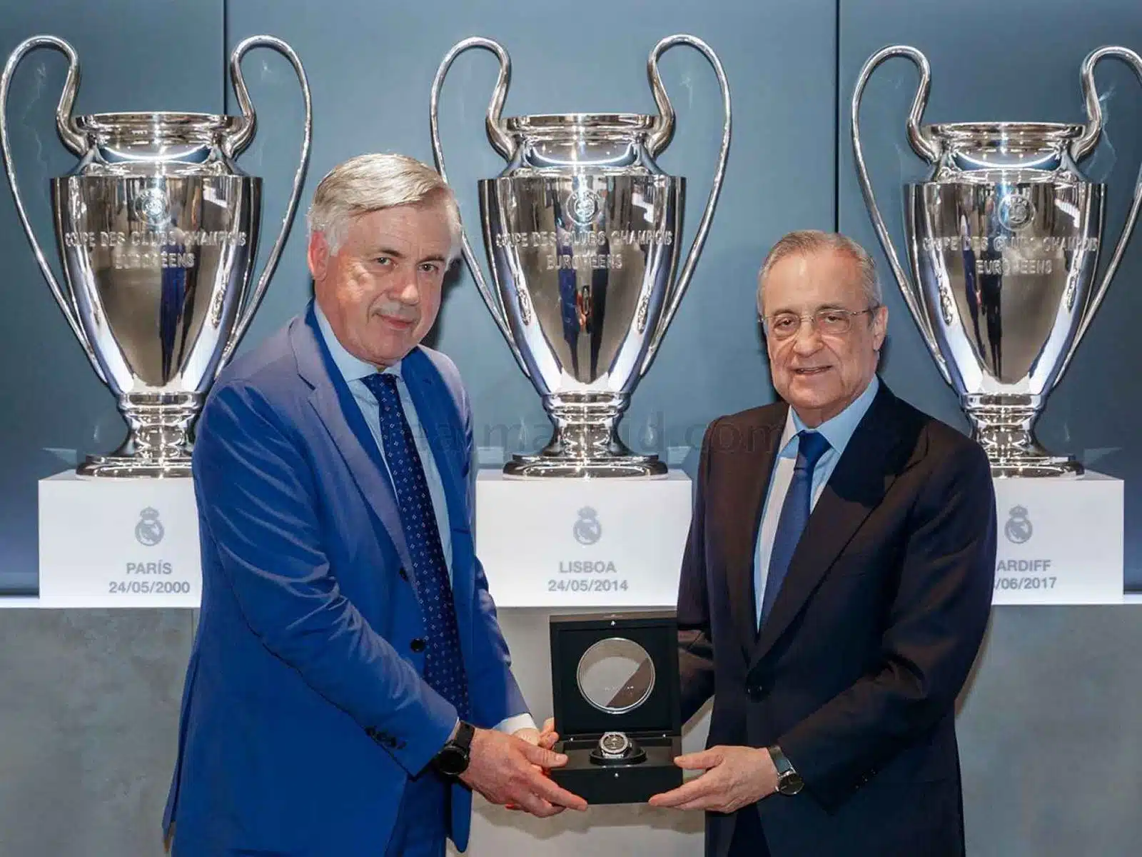 Carlo Ancelotti junto a una persona con un trofeo en sus manos y otros 3 al fondo