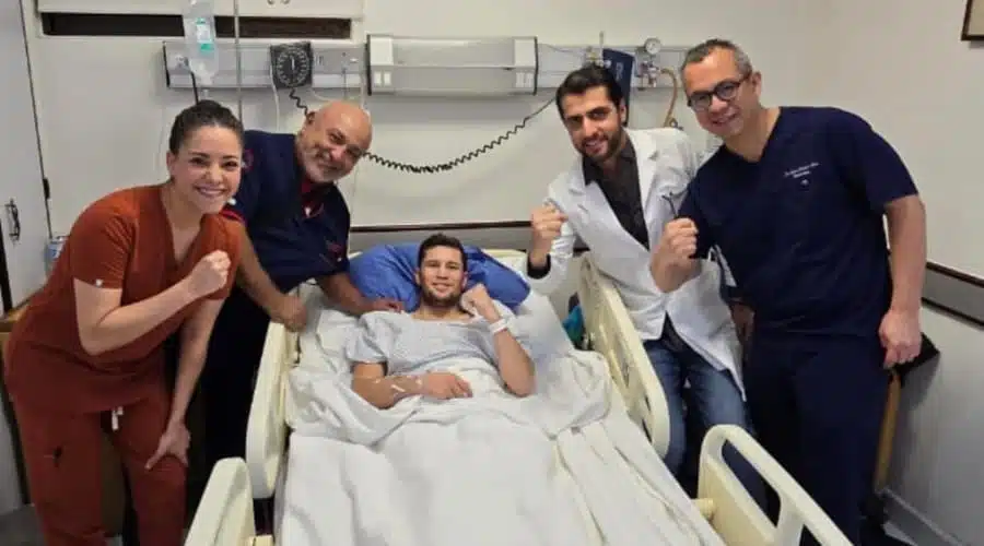 Boxeador Carlos Cuadras en una cama de hospital posando para una foto junto a un equipo de médicos