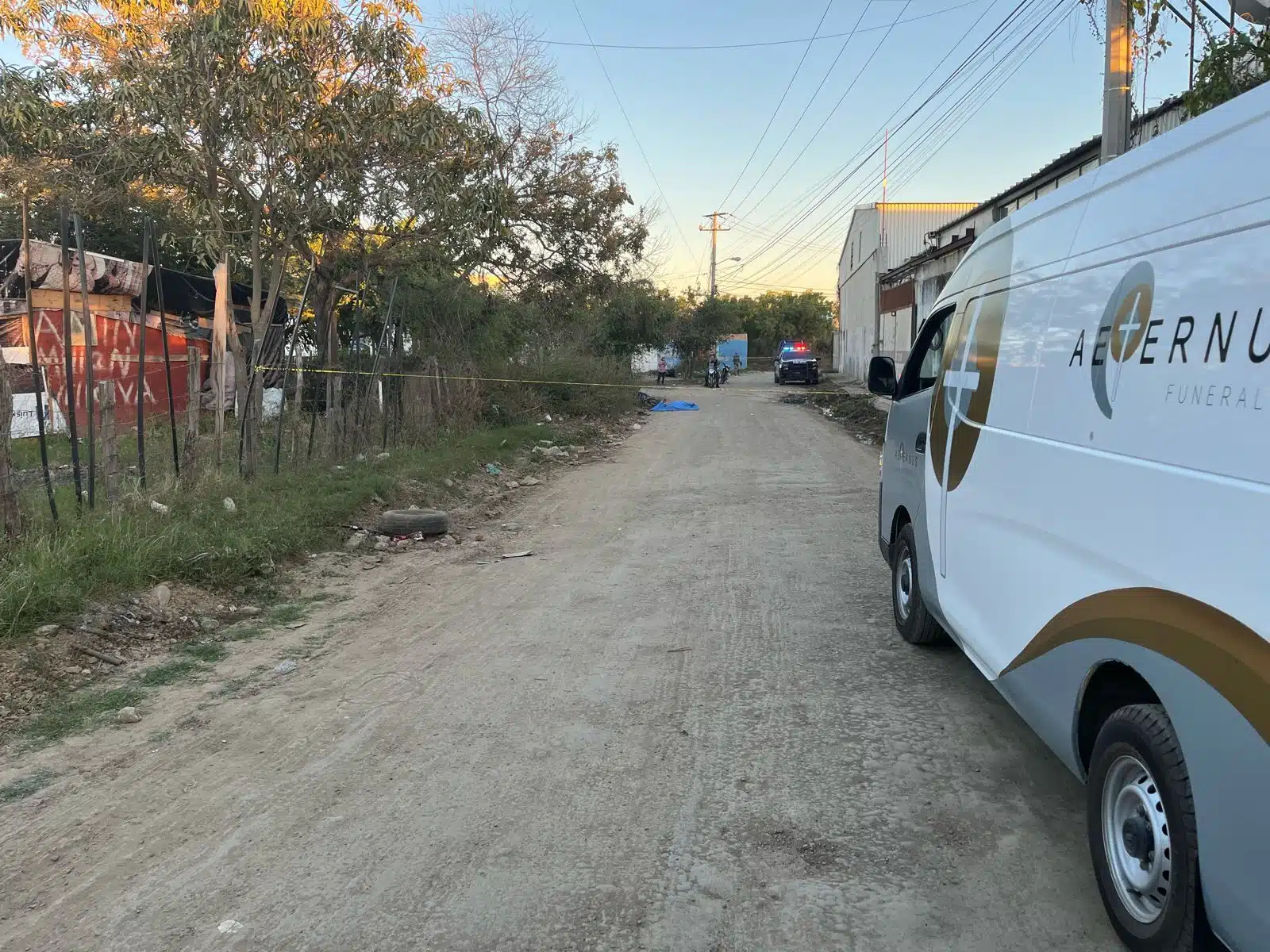Camioneta de una funeraria, patrulla de la Policía Municipal en lugar donde encontraron el cuerpo de un hombre en Mazatlán