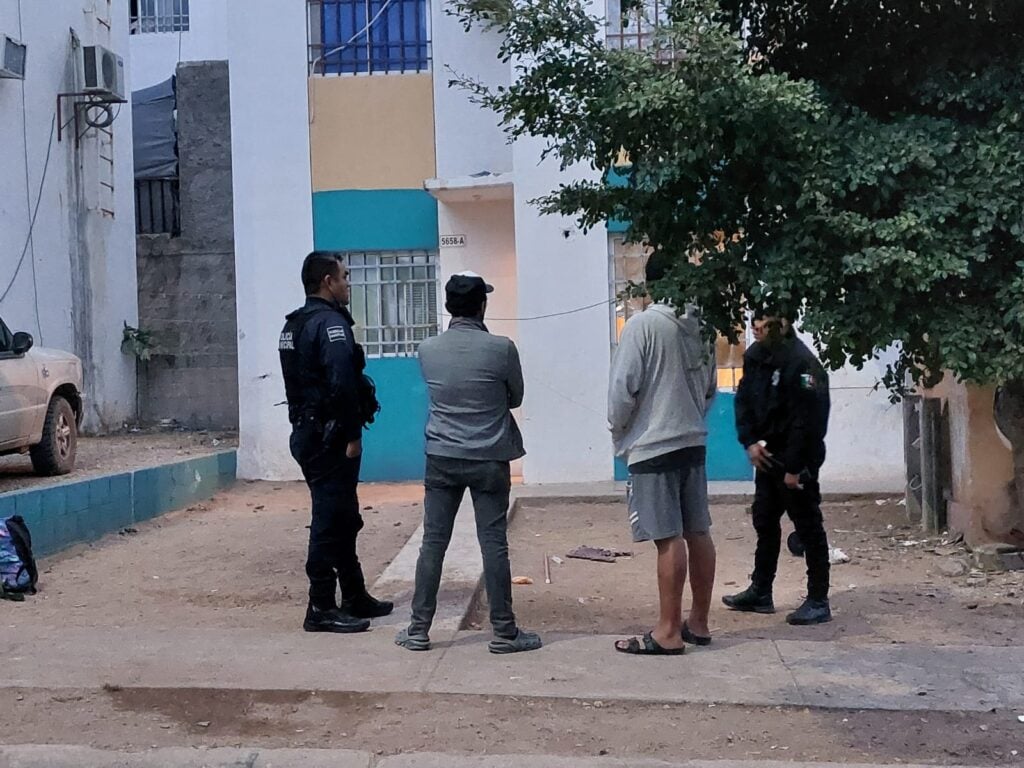 Policías y vecinos al exterior de una vivienda donde se registró un homicidio