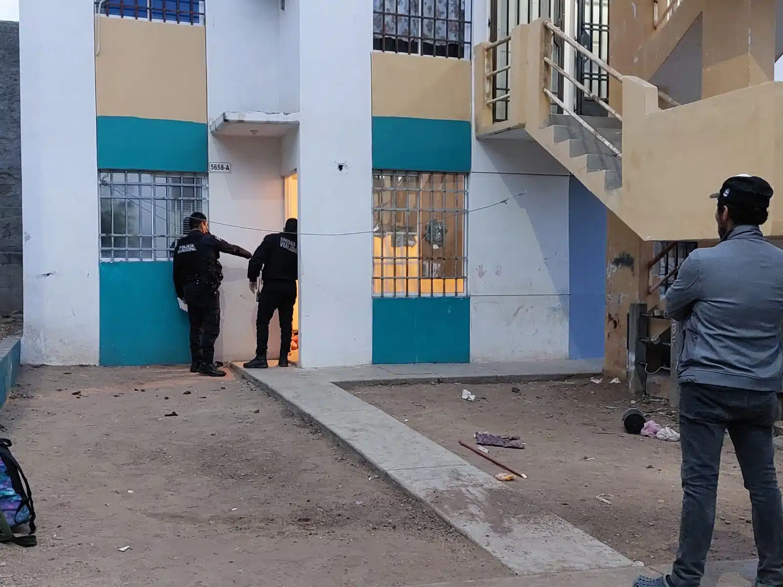 Policías y vecinos al exterior de una vivienda donde se registró un homicidio