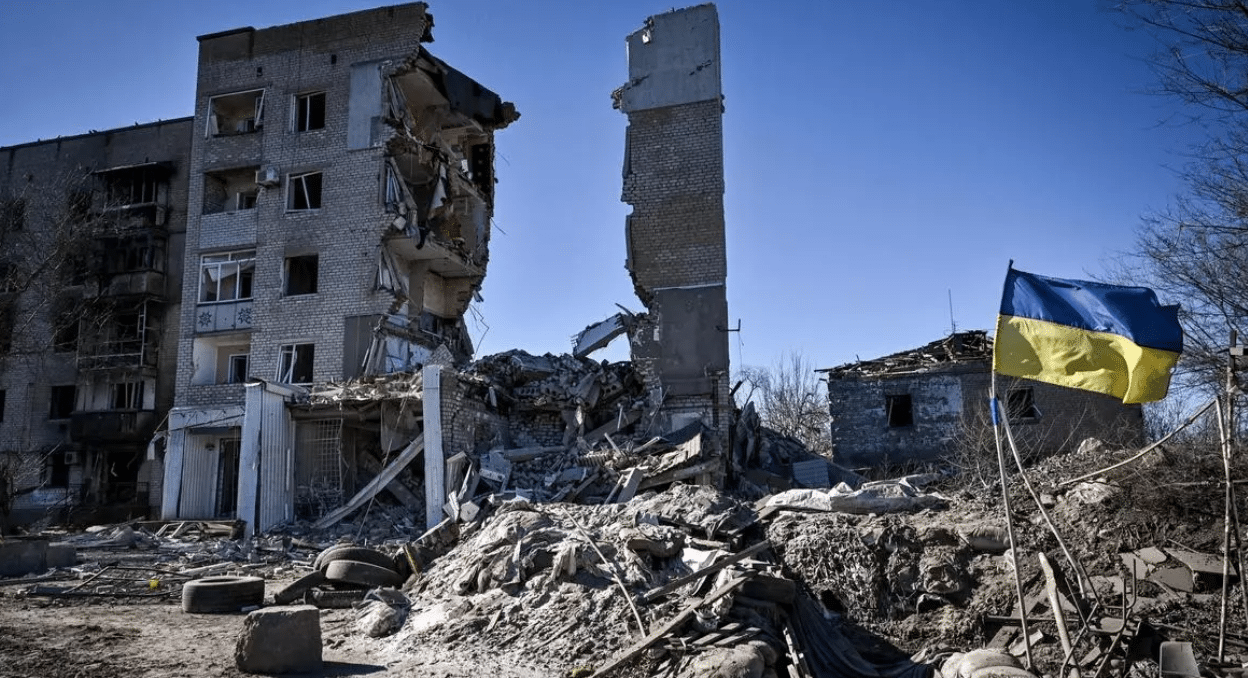 Bandera de Ucrania ondea delante de un edificio destruido