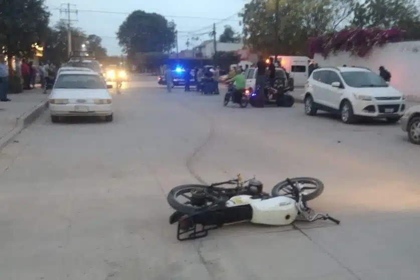 Motocicleta tendida en el suelo después de una embestida por una camioneta