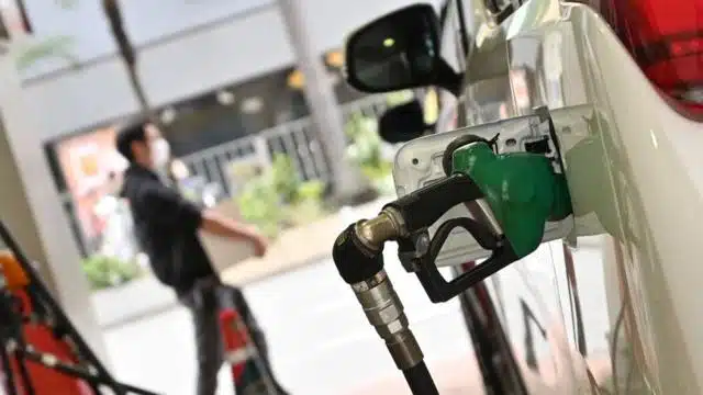 Manguera de una bomba de gasolina cargando combustible a un carro color blanco