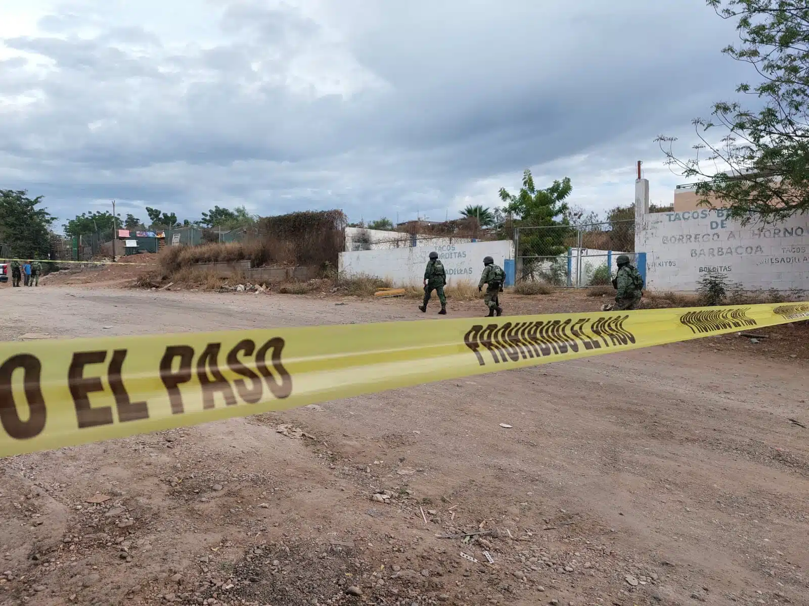 Calle de terracería acordonada con cinta amarilla y elementos del Ejército y de la Policía Municipal en la zona donde encontraron a una persona asesinada