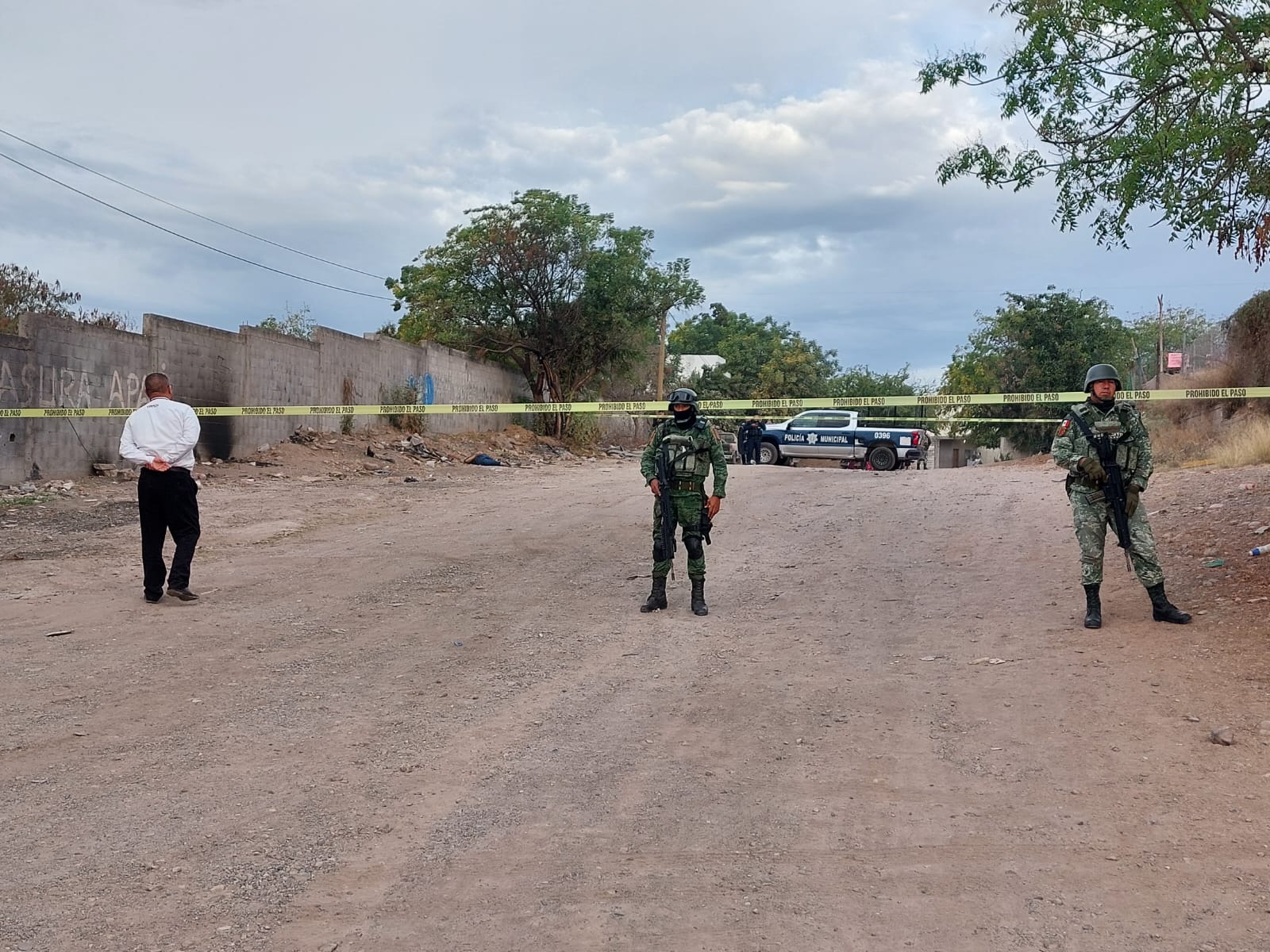 Calle de terracería acordonada con cinta amarilla y elementos del Ejército y de la Policía Municipal en la zona donde encontraron a una persona asesinada