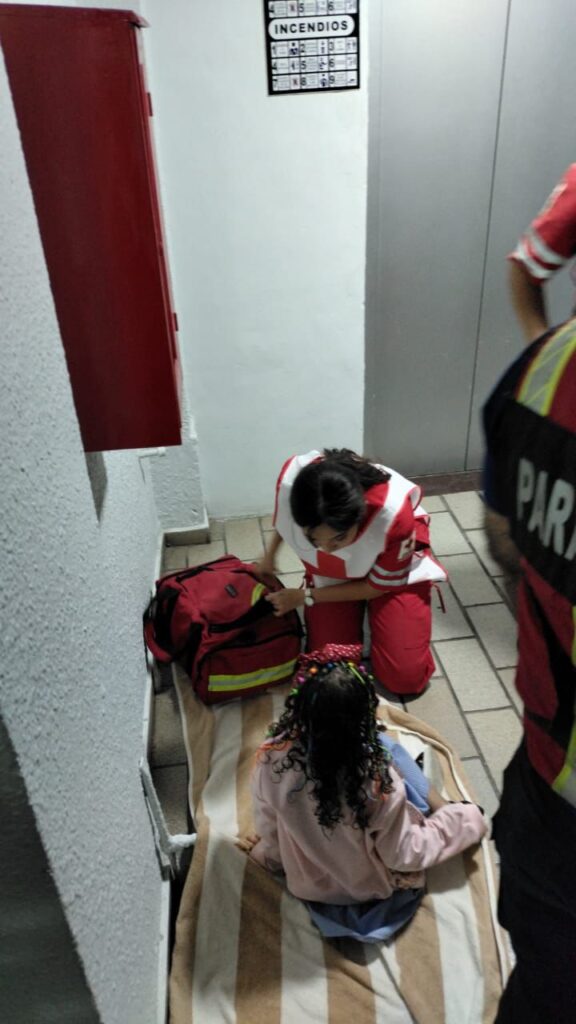 Paramédico de la Cruz Roja atendiendo a una niña que fue rescatada de el elevador de un hotel en Mazatlán