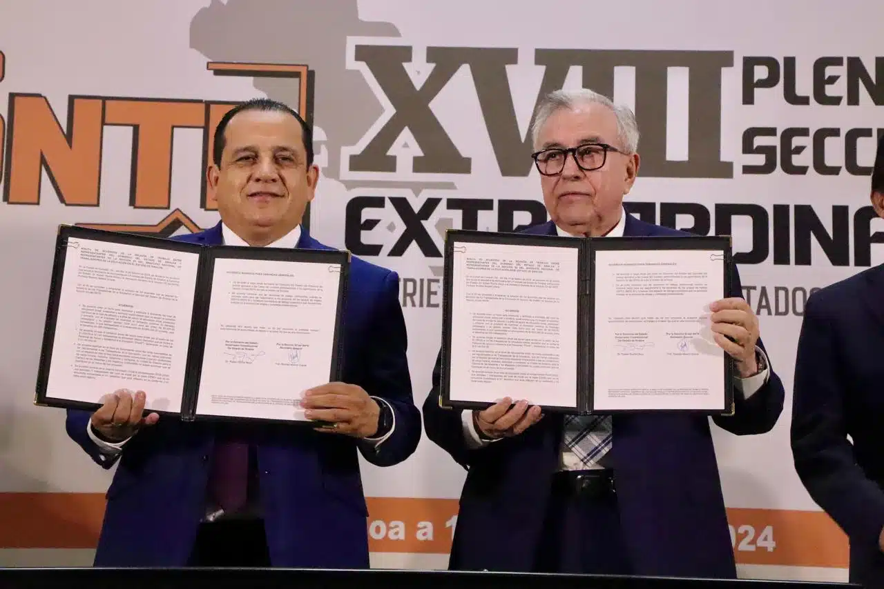Rubén Rocha Moya, gobernador de Sinaloa, y Ricardo Madrid Uriarte, secretario general de la Sección 53 del SNTE, con un documento en sus manos en un evento en Culiacán