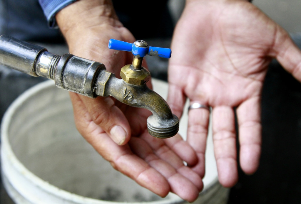 Manos por debajo de una llave en espera de que salga agua