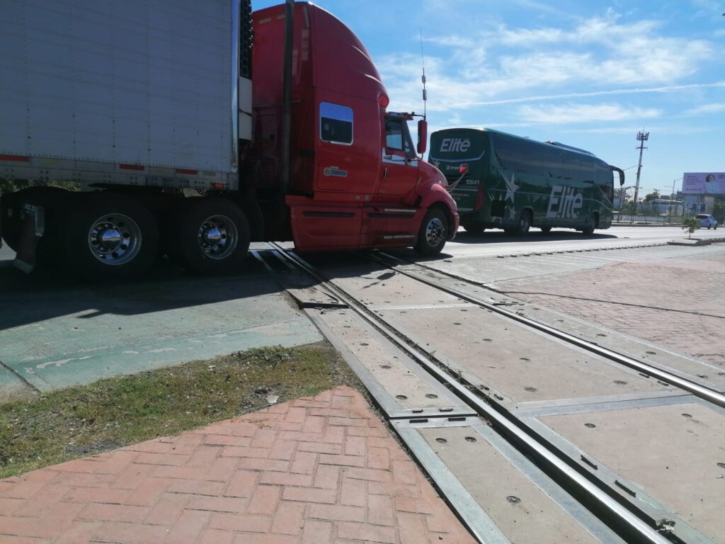 Tráiler y autobús pasando por el cruce de las vías del tren en Culiacán