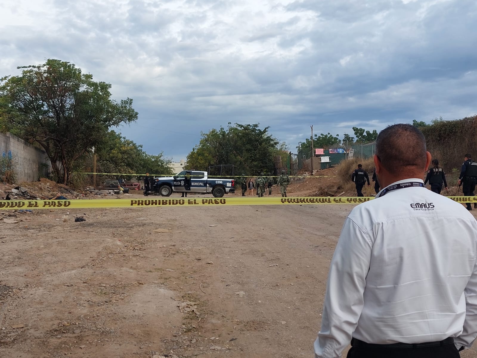 Calle de terracería acordonada con cinta amarilla y elementos del Ejército y de la Policía Municipal en la zona donde encontraron a una persona asesinada