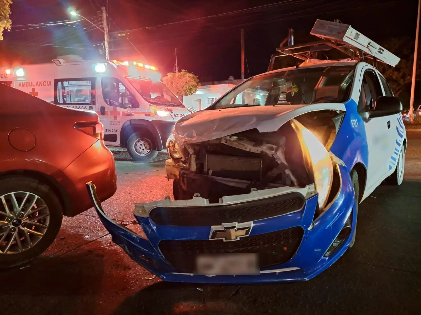 Vehículo empresarial con la defensa delantera caída. Al fondo hay una ambulancia.