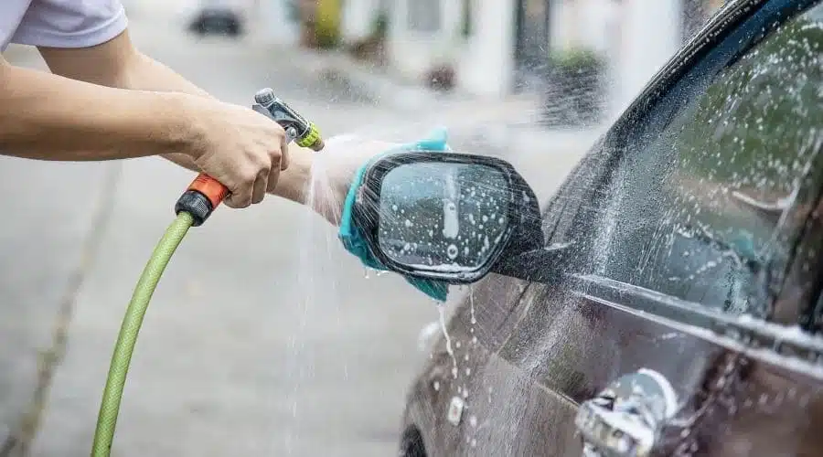 Persona lavando automóvil con agua potable