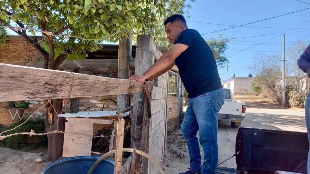 Una persona echándole agua a un tambo ante la sequía en Choix