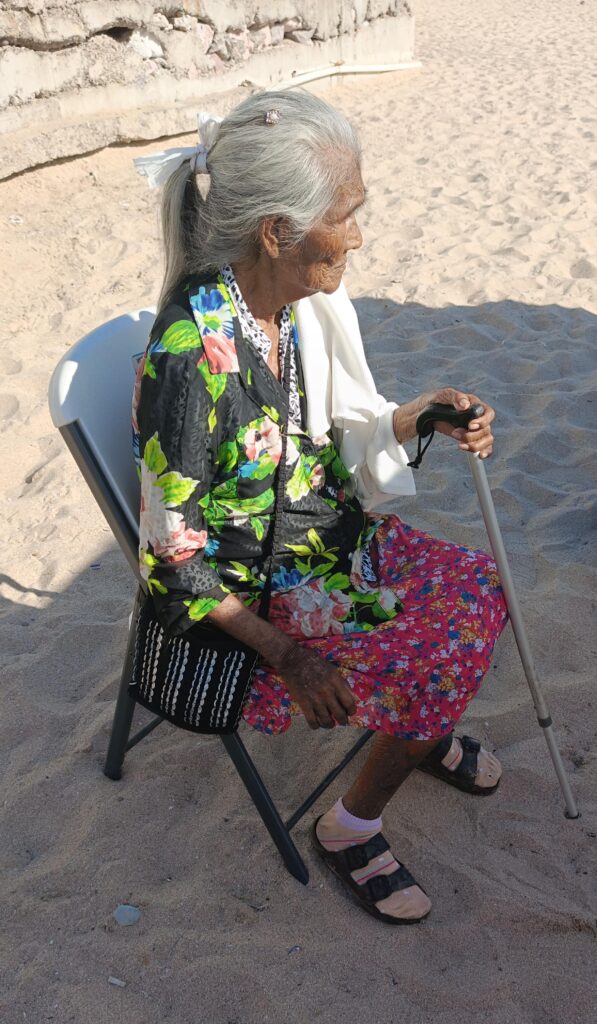 Bisabuela de Jorge sentada en una silla en la arena de la playa en Mazatlán
