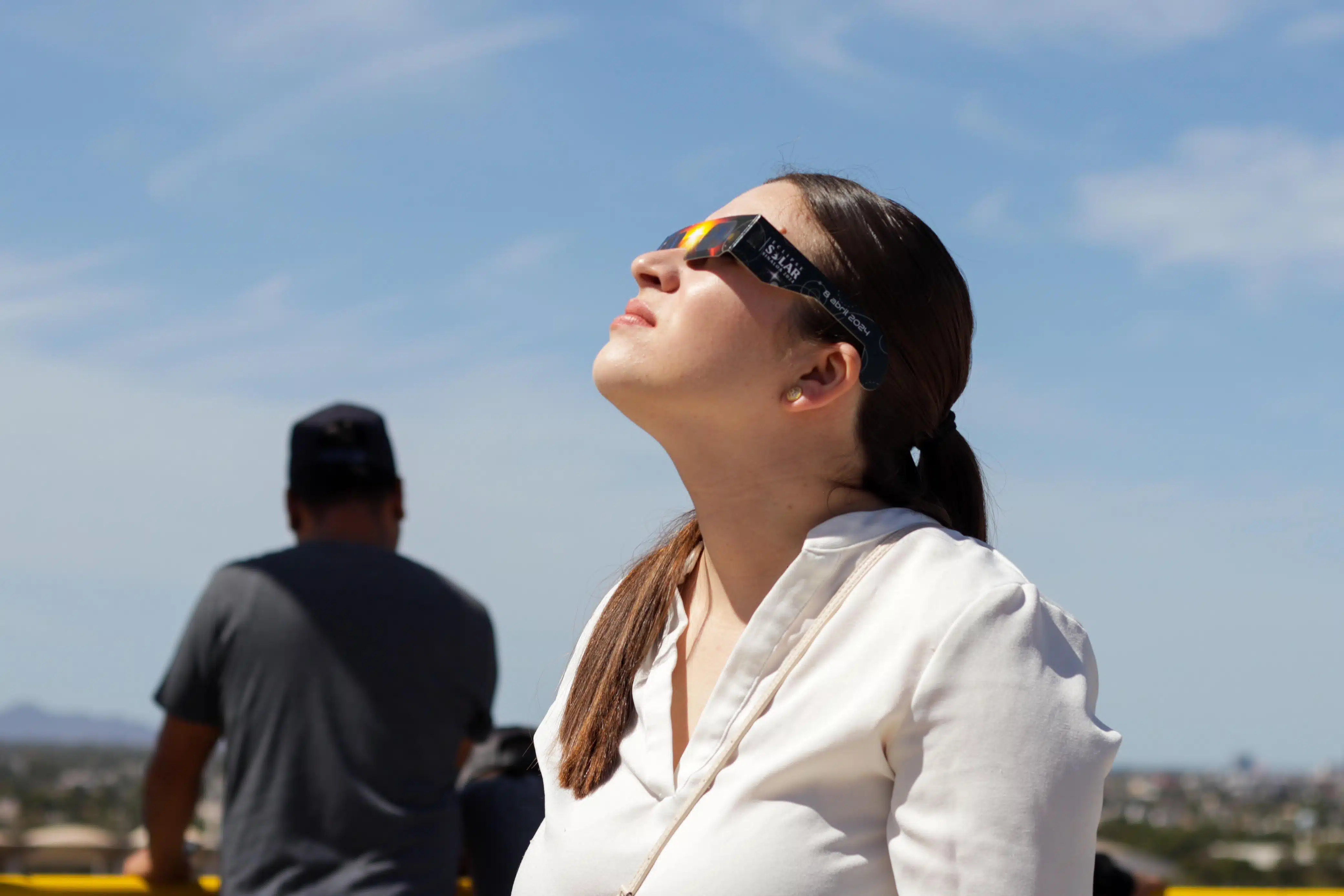 Joven mujer observando el eclipse solar con unos lentes especiales