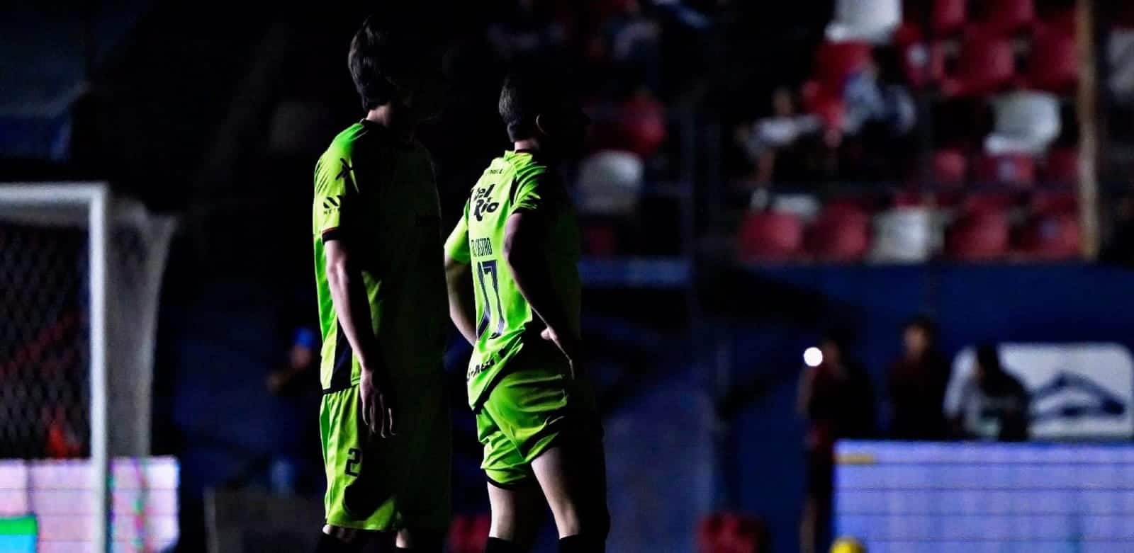 Jugadores de futbol en el campo a oscuras por fallas en alumbrado del estadio