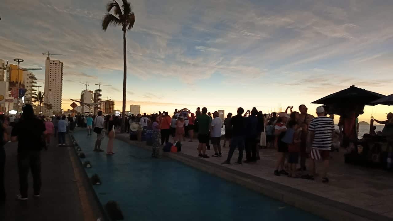 Personas en el malecón de Mazatlán observando el eclipse total de Sol