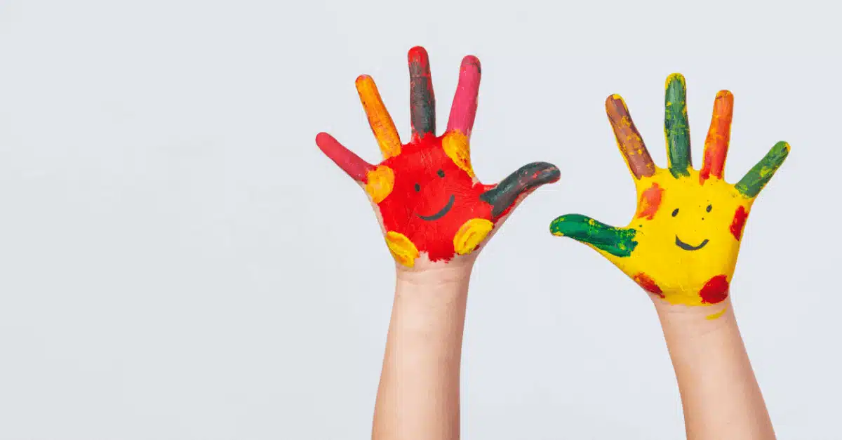 Manos de un infante pintadas de colores y con caritas felices
