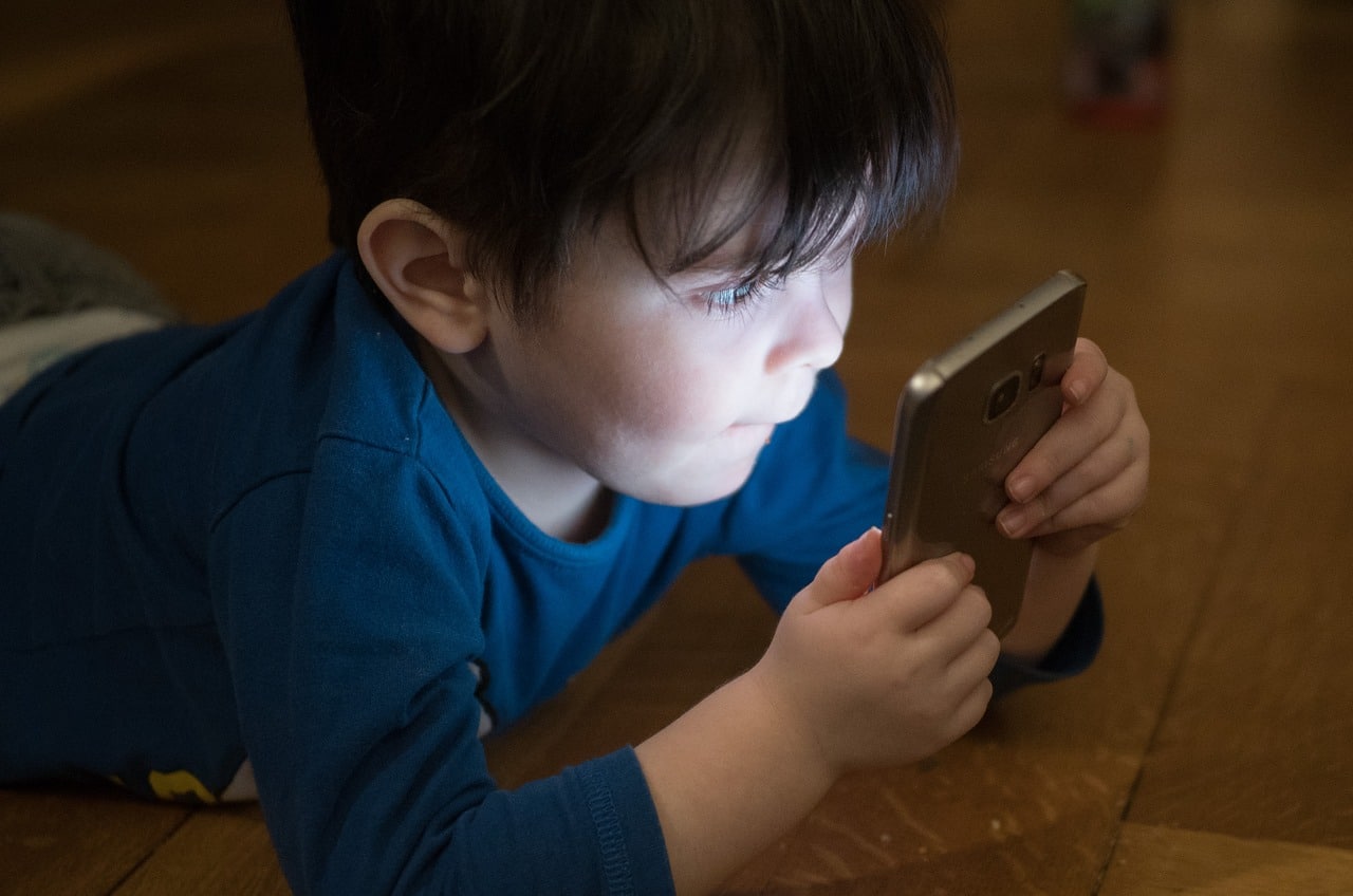 Niño sosteniendo un celular con sus manos