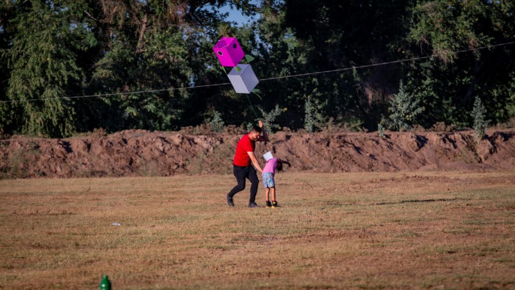 Niña y su padre volando un papalote durante concurso en Guasave