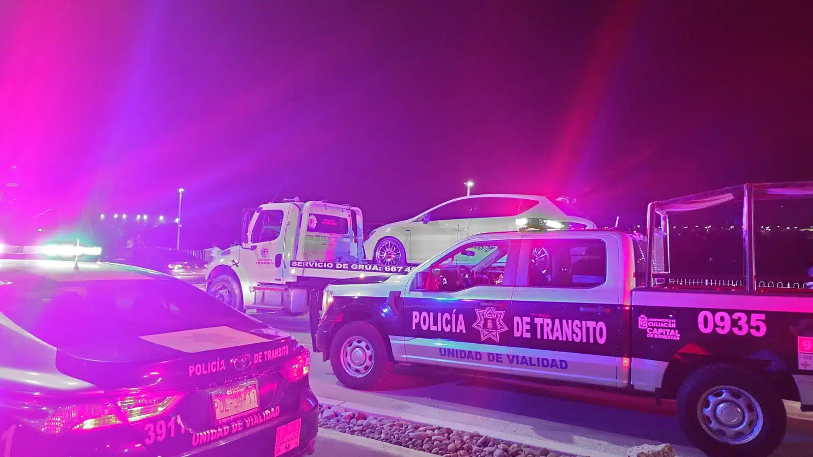 Patrullas de la Policía Municipal, al fondo un carro arriba de una grúa durante un operativo en Culiacán