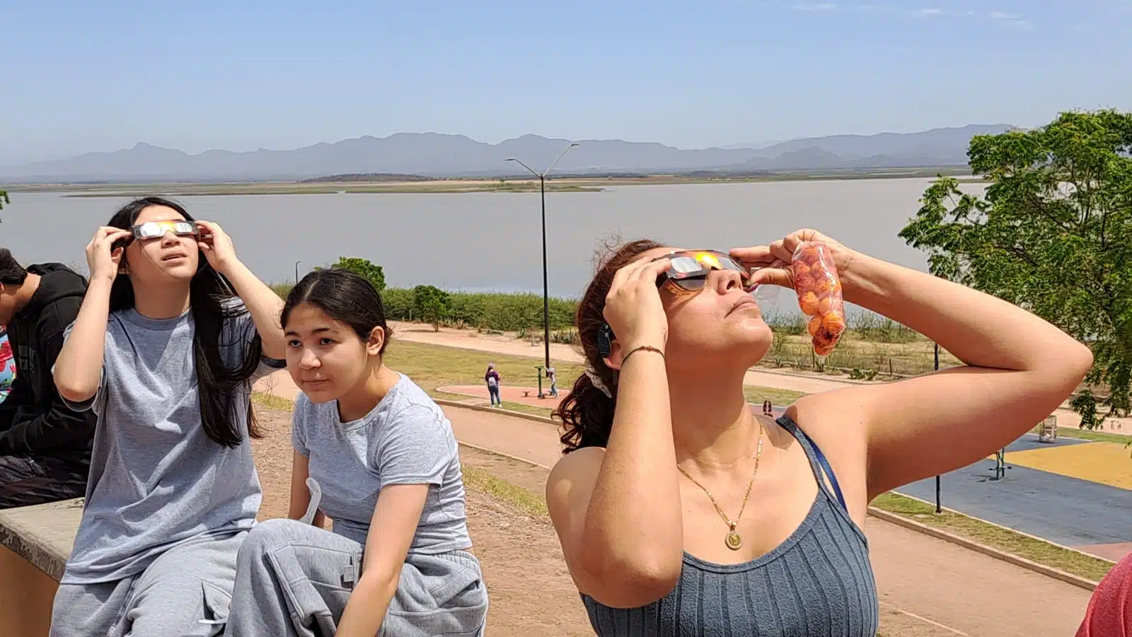 Personas en la presa Eustaquio Buelna mirando al cielo para apreciar el eclipse total de Sol en Guamúchil