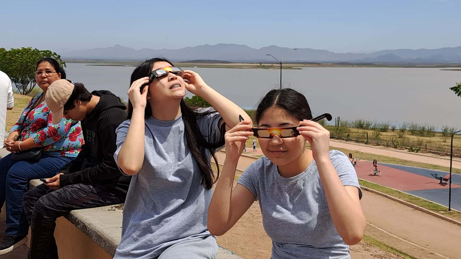 Personas en la presa Eustaquio Buelna mirando al cielo para apreciar el eclipse total de Sol en Guamúchil