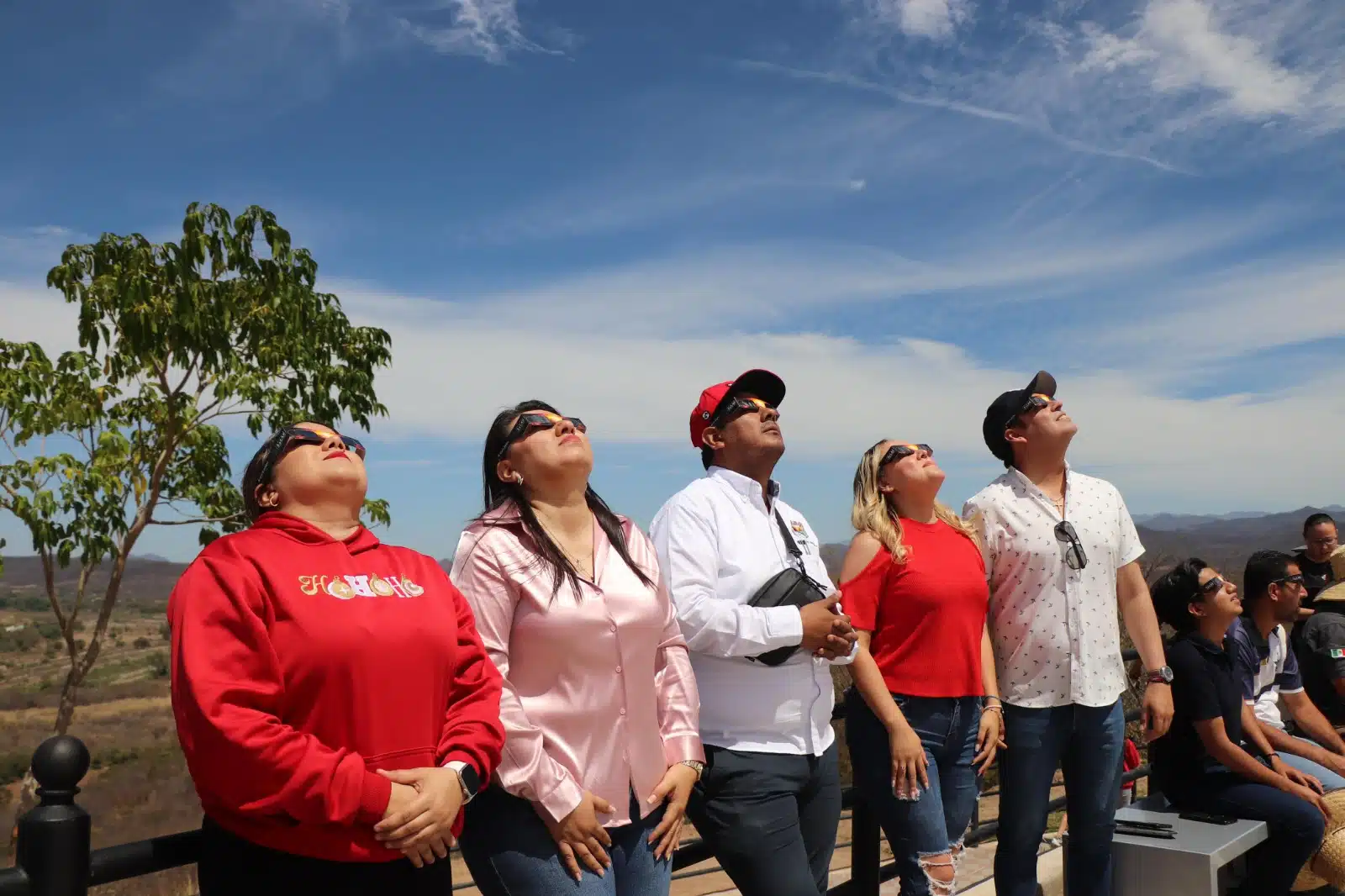Personas en el parque Mirador de Badiraguato junto a San Judas Tadeo volteando al cielo para apreciar el eclipse total de Sol