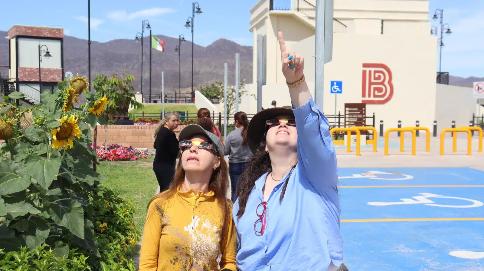 Personas en el parque Mirador de Badiraguato junto a San Judas Tadeo volteando al cielo para apreciar el eclipse total de Sol