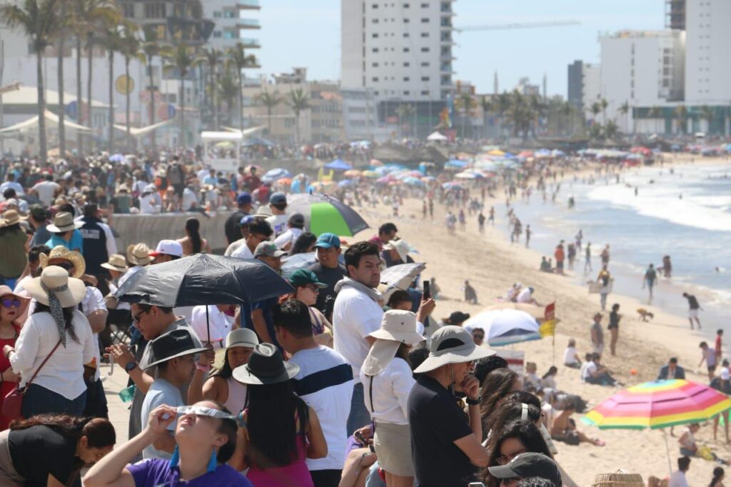 Personas en la orilla del mar en Mazatlán observando el eclipse total de Sol